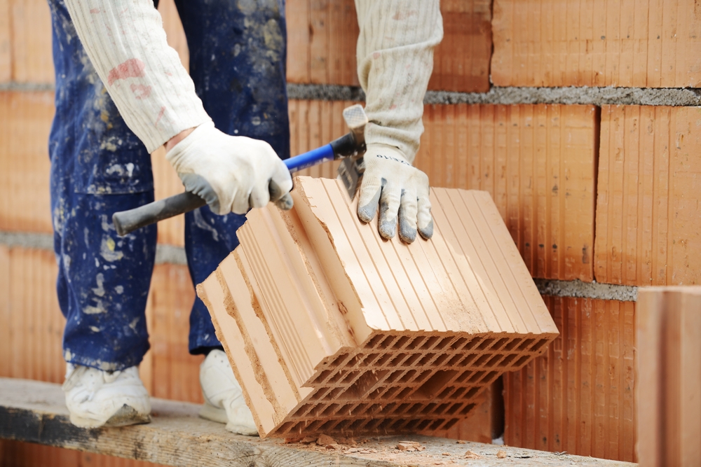 Worker building on wet layer concrete, brick wall