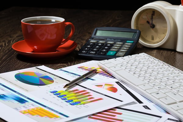 Workplace with keyboard cup of coffee and graphs-1