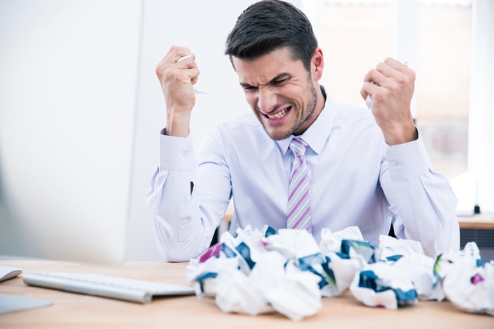 Upset businessman sitting at the table with crumpled paper in office.jpeg