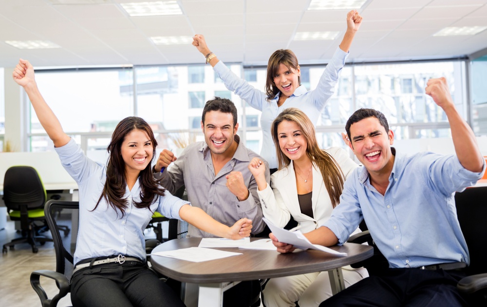 Successful business team with arms up at the office